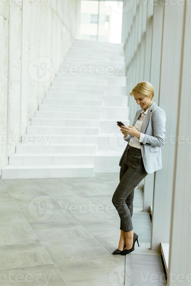 femme d'affaires utilisant un téléphone portable dans un couloir de bureau moderne photo