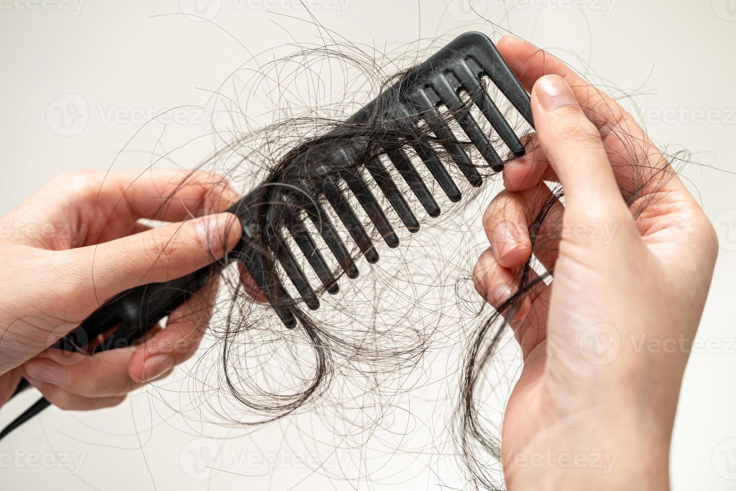 une femme asiatique a un problème avec la perte de cheveux longs attachée à la brosse à peigne. photo