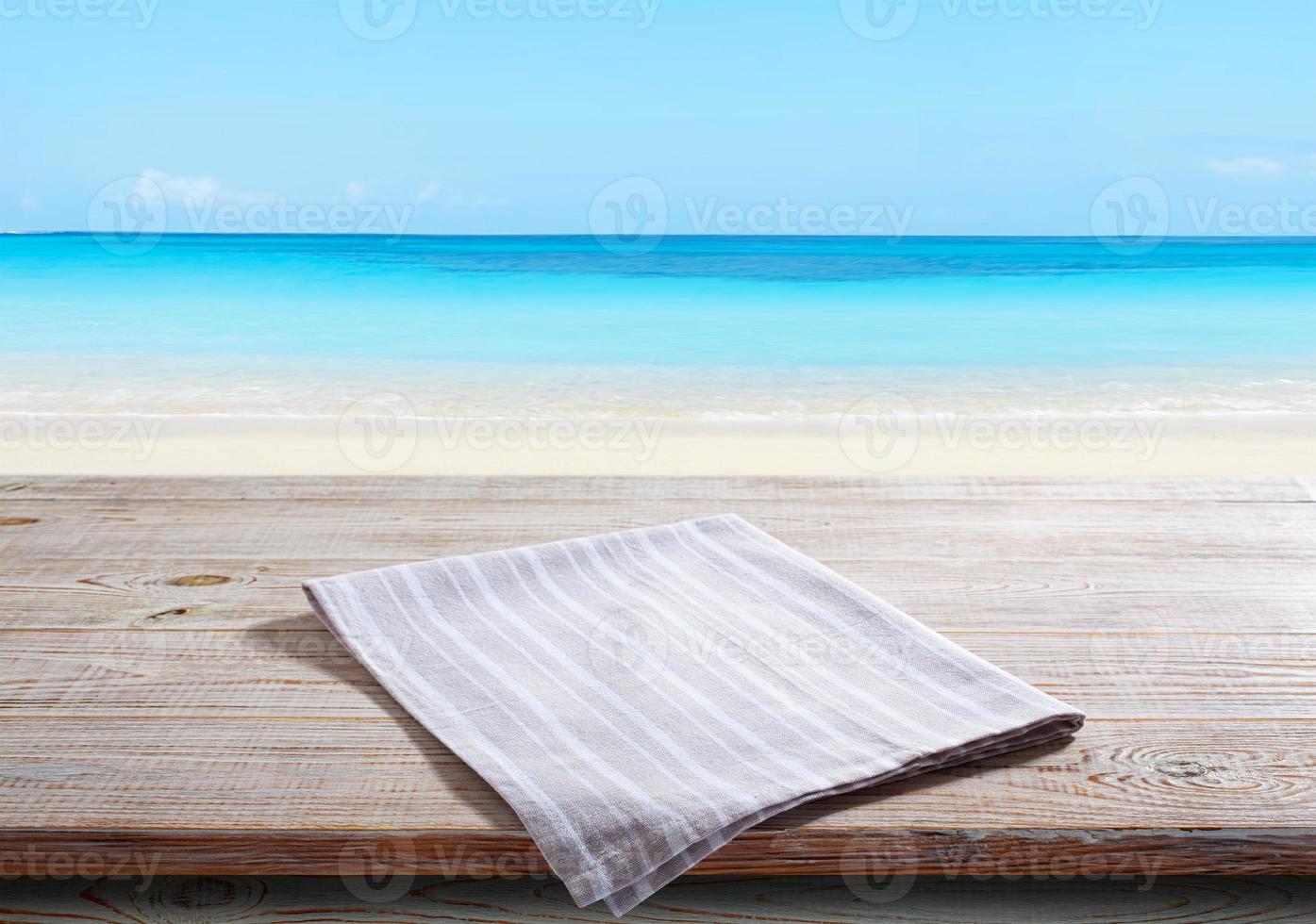 serviette blanche, nappe sur maquette de terrasse en bois. fond de plage de la mer photo