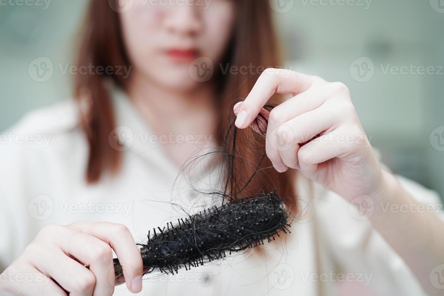 une femme asiatique a un problème avec la perte de cheveux longs attachée à la brosse à peigne. photo