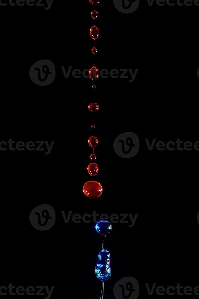 chute de gouttes de liquide coloré, éclaboussures sur fond noir, flou de mouvement photo