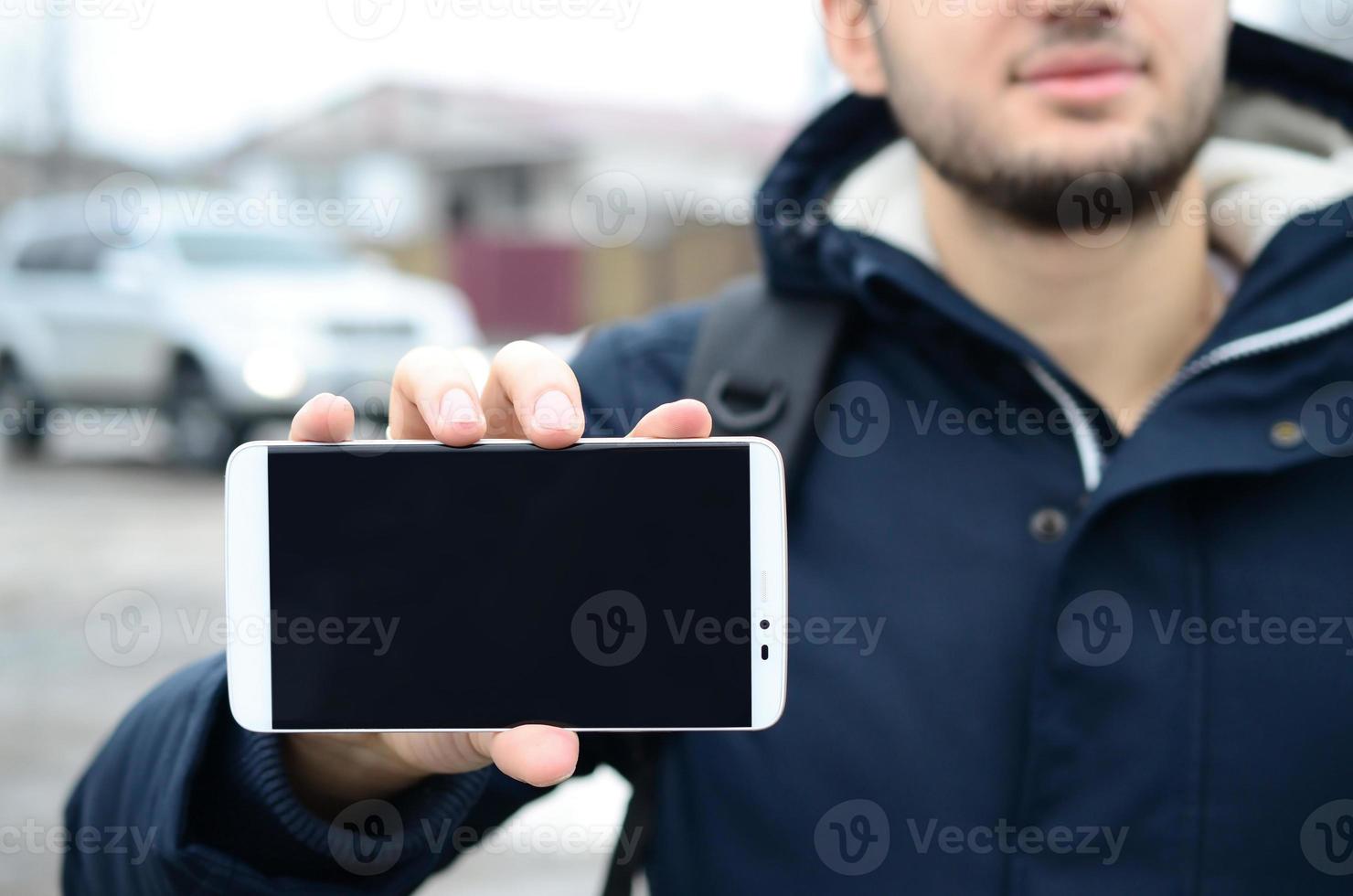 un jeune homme montre un écran de smartphone en arrière-plan photo