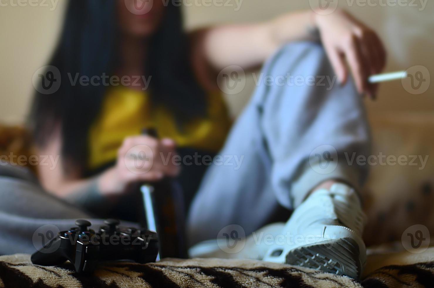 une fille assise sur le canapé, fumant une cigarette, buvant de la bière photo