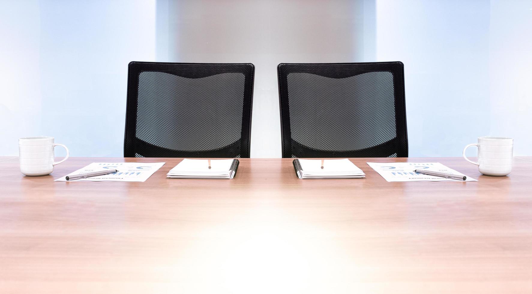 deux fauteuils noirs avec de la paperasse et une tasse de café sur la table dans la salle de réunion photo