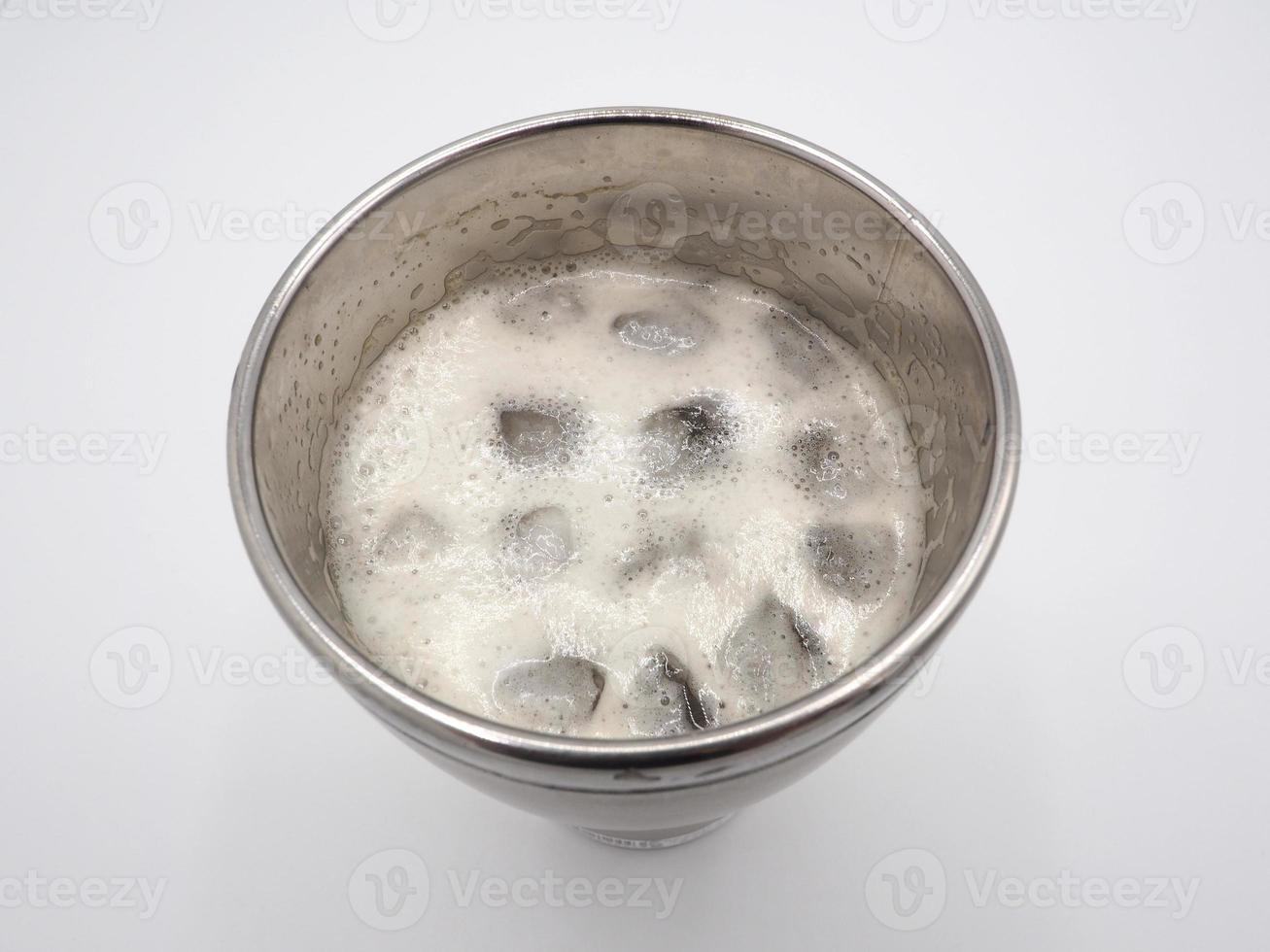 bulles de mousse de bière blanche et gros plan de glaçons dans la vue de dessus de la tasse thermos en acier inoxydable et fond blanc. photo