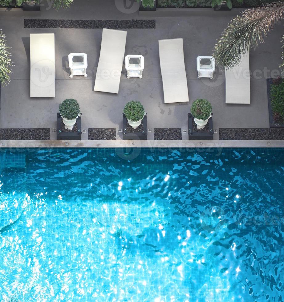 piscine eau bleue en été et lits de plage blancs et angle de vue de dessus. photo