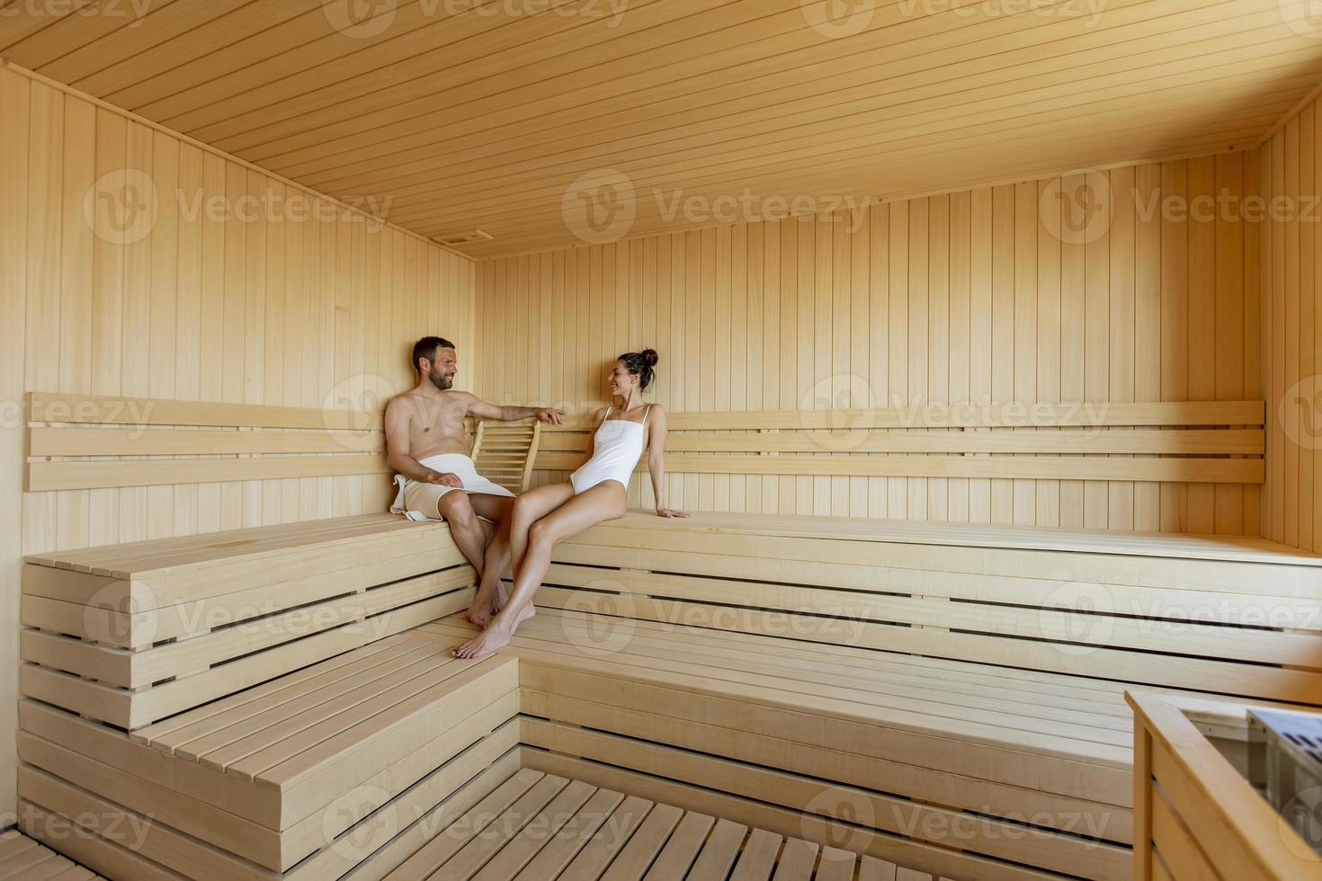 jeune couple se détendre dans le sauna et regarder la forêt d'hiver par la fenêtre photo