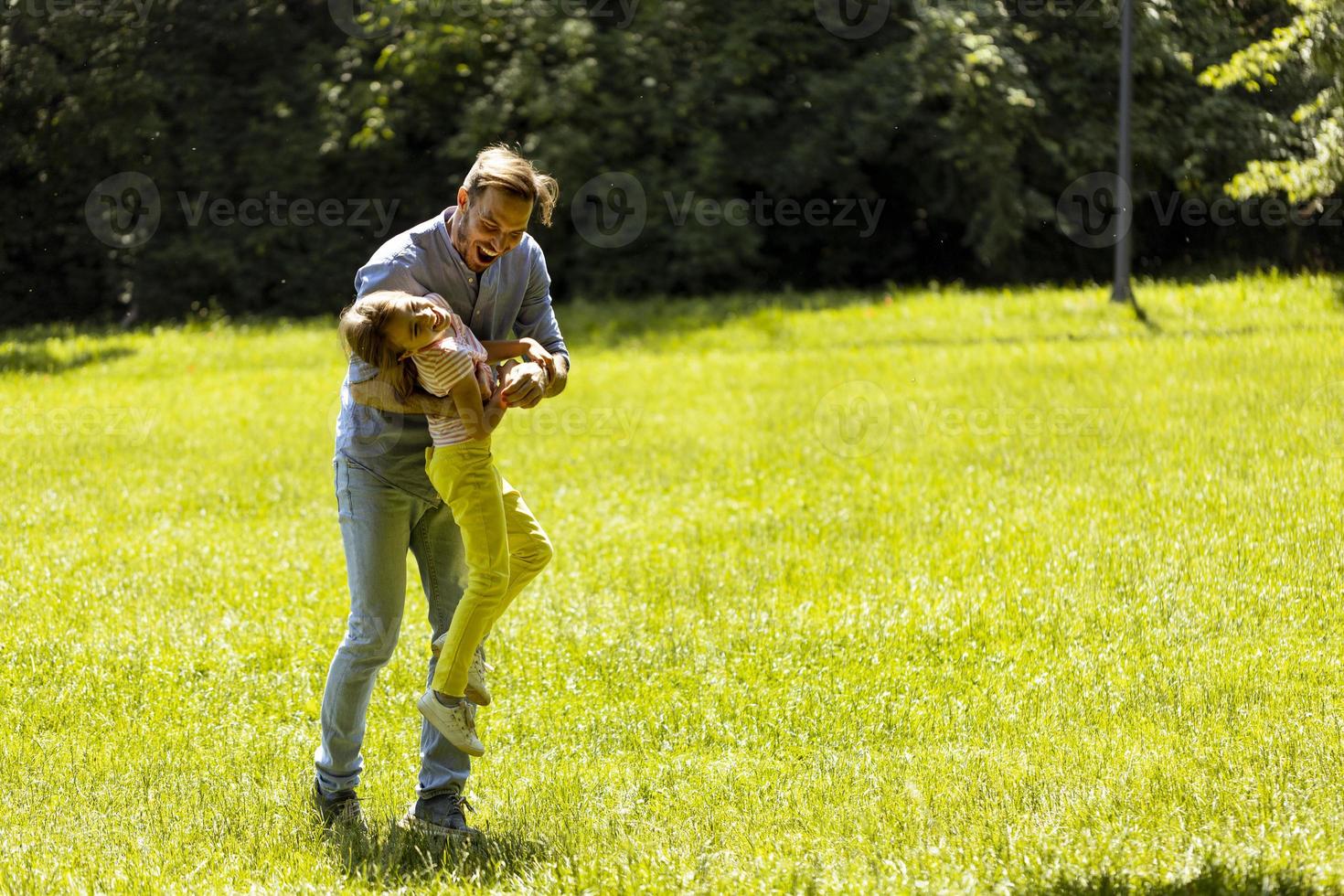 père avec fille s'amusant sur l'herbe au parc photo