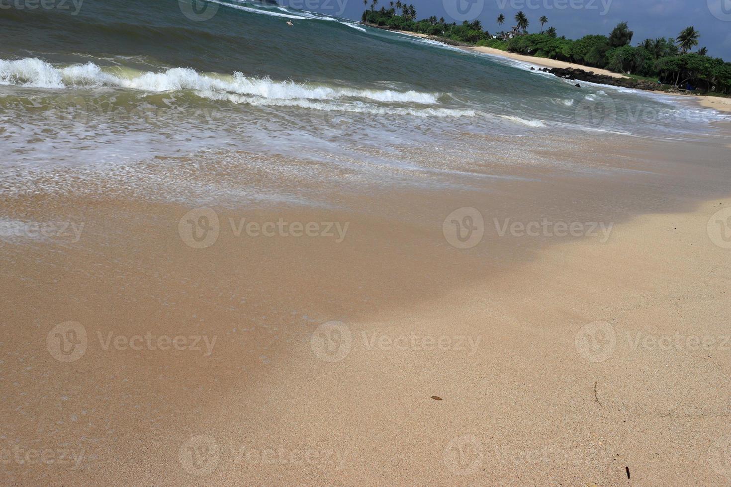 rivage de l'océan avec plage de sable et vague qui avance. mousse d'eau avec du sable lisse. belles vagues sur le fond de la plage de sable. photo