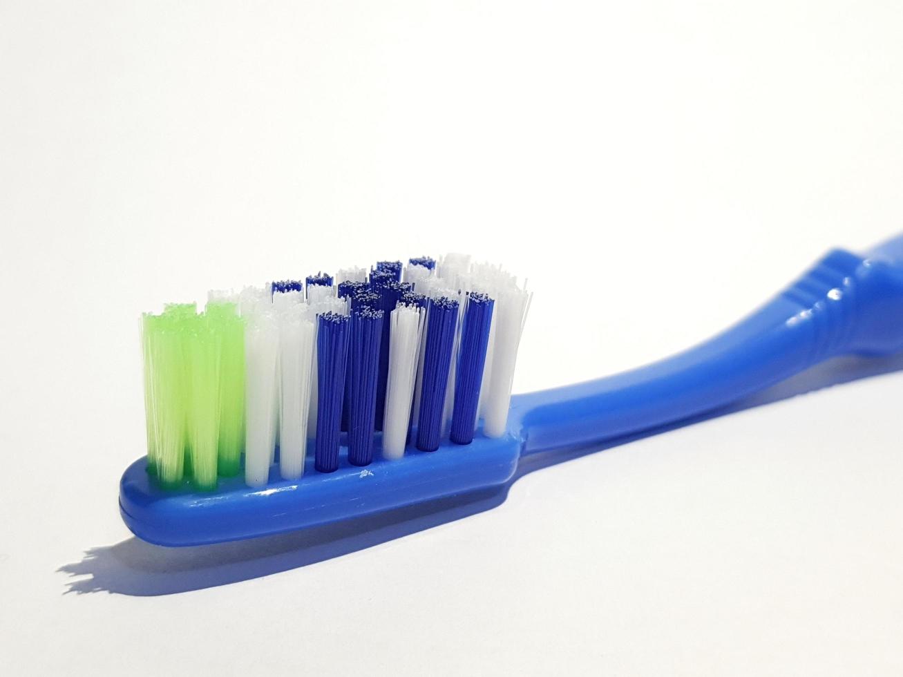 photo blanche isolée d'une brosse à dents en plastique qui a été utilisée plusieurs fois. cette brosse à dents a un manche bleu.