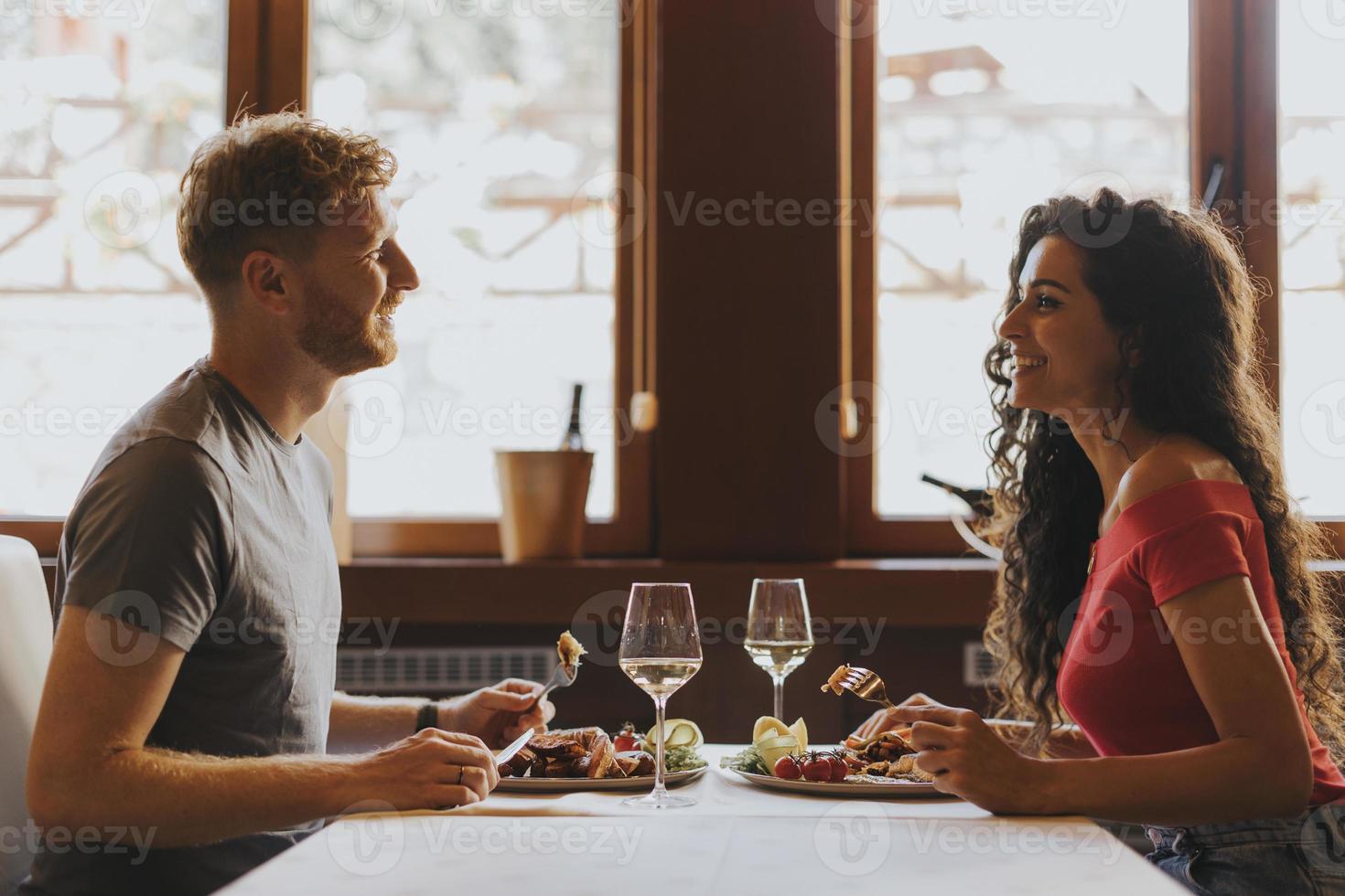 jeune couple en train de déjeuner avec du vin blanc au restaurant photo