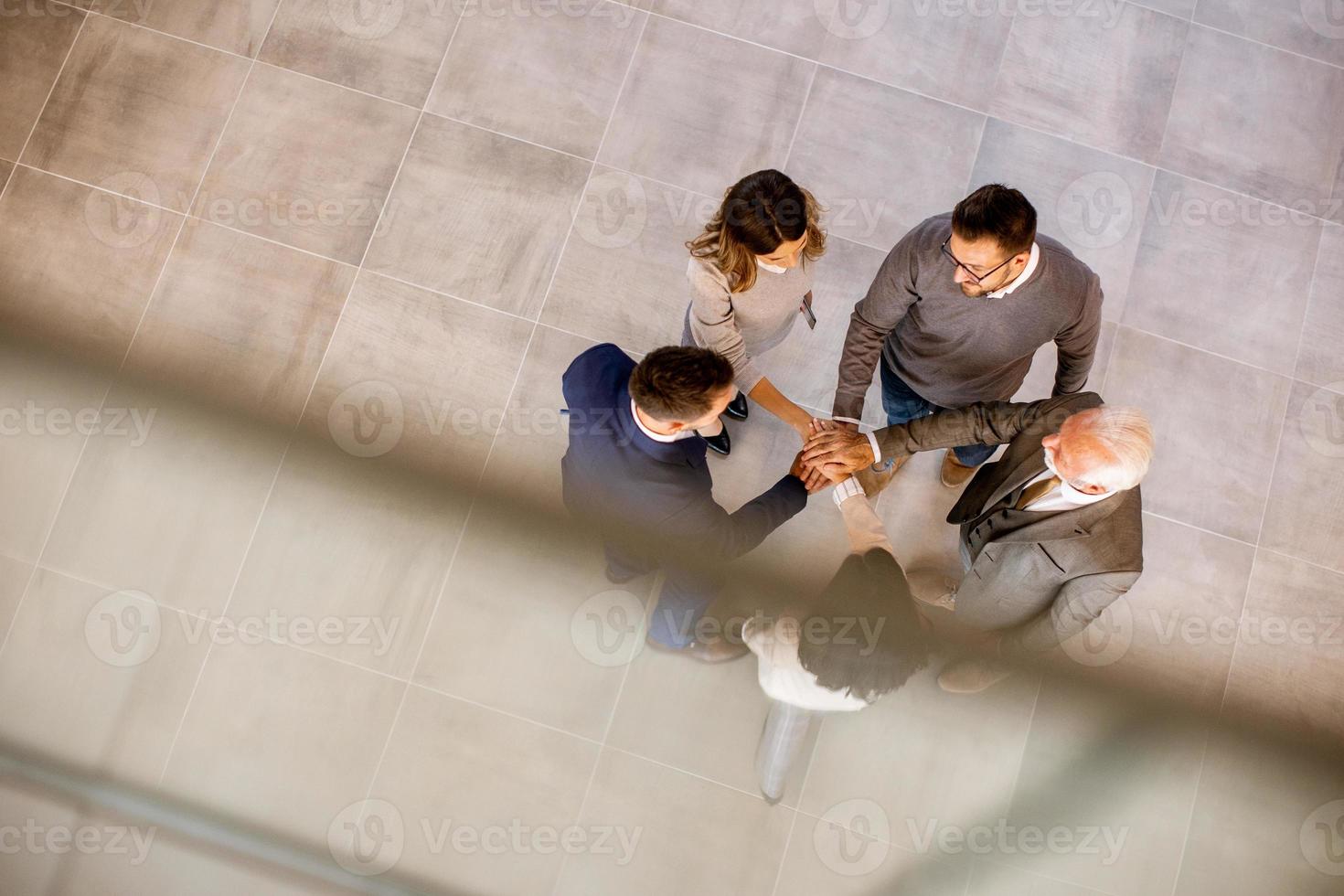 L'équipe de gens d'affaires empile les mains comme un geste d'unité dans le couloir du bureau photo