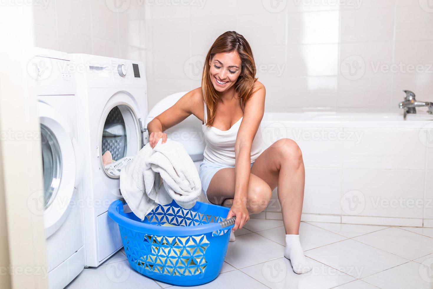 jeune femme sortant le linge de la machine à laver à la maison, gros plan d'une machine à laver chargée de vêtements, prenant à la main des serviettes de couleur photo