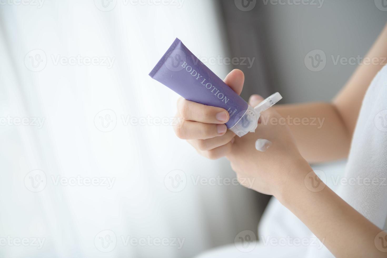 gros plan de femmes appliquant une crème de lotion pour le corps à portée de main. photo