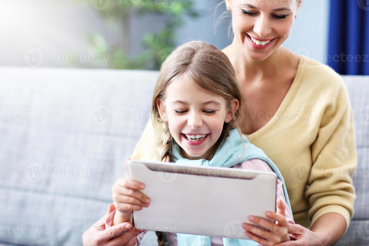 petite fille et sa mère à l'aide d'une tablette assise sur un