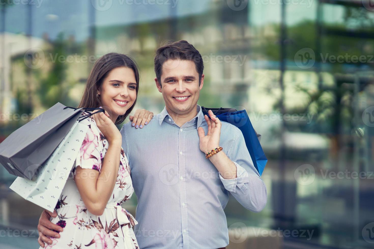 portrait d'un couple heureux avec des sacs à provisions en ville souriant et étreignant. photo