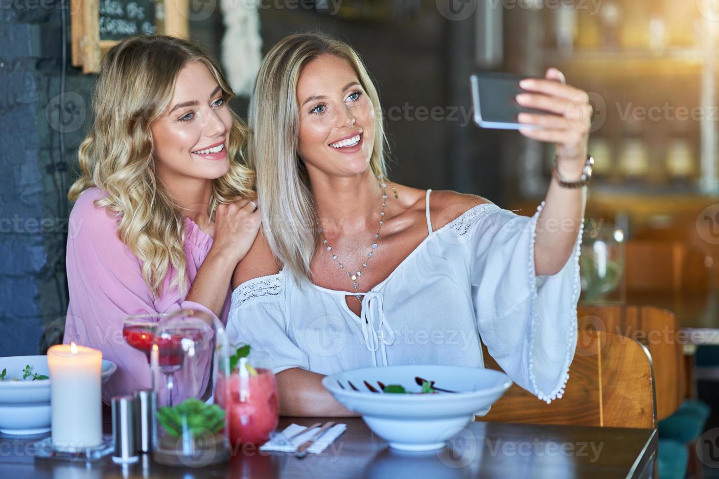 deux amies en train de déjeuner au restaurant et à l'aide d'un smartphone photo