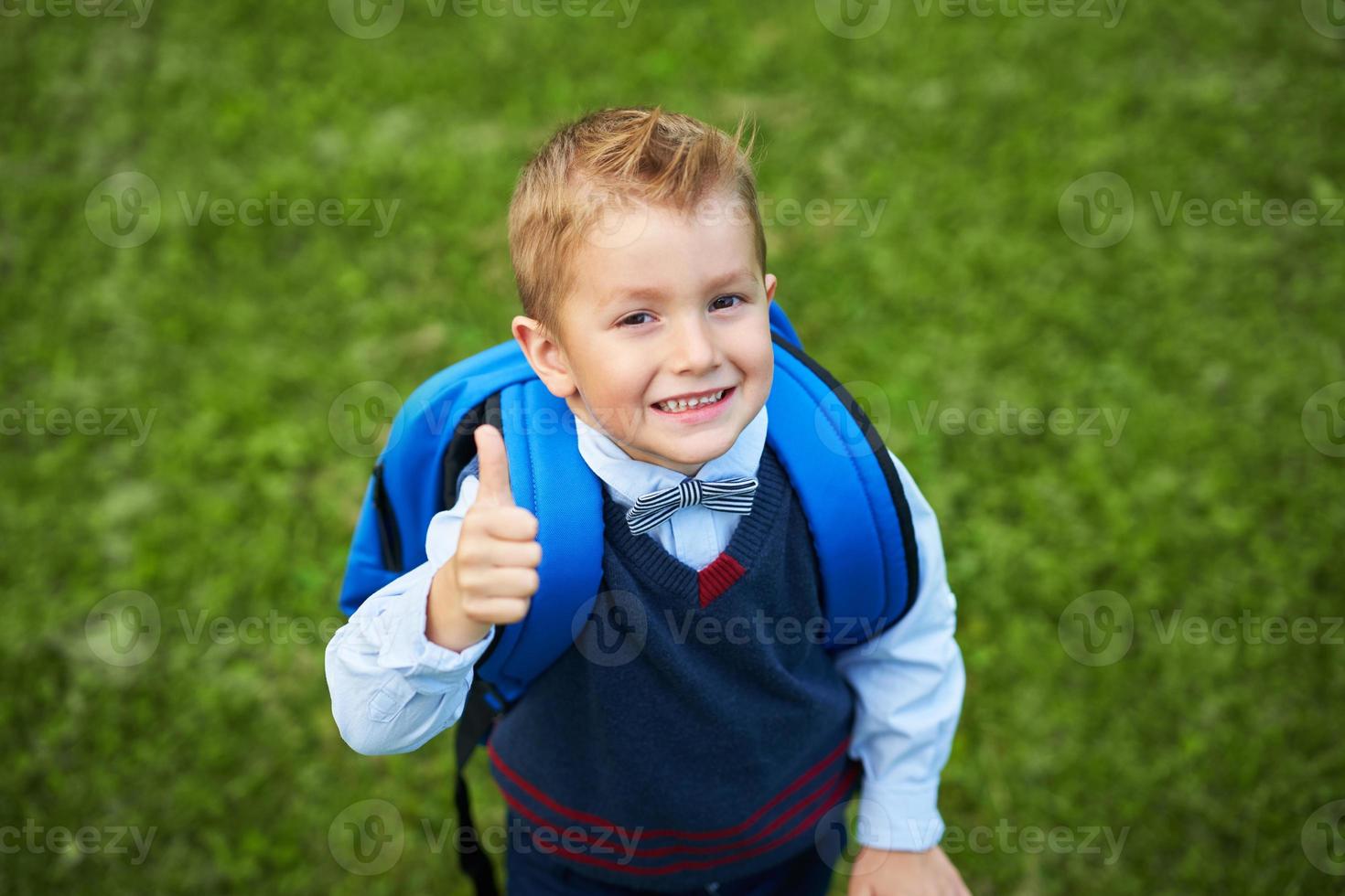 heureux petit garçon enfant d'âge préscolaire avec sac à dos posant à l'extérieur photo