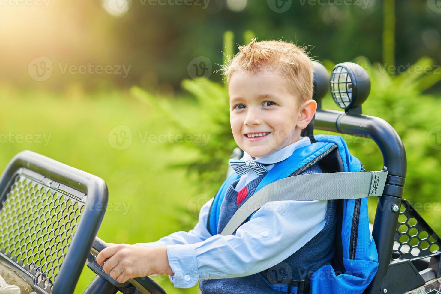 écolier conduisant une voiture pour enfants avec sac à dos photo
