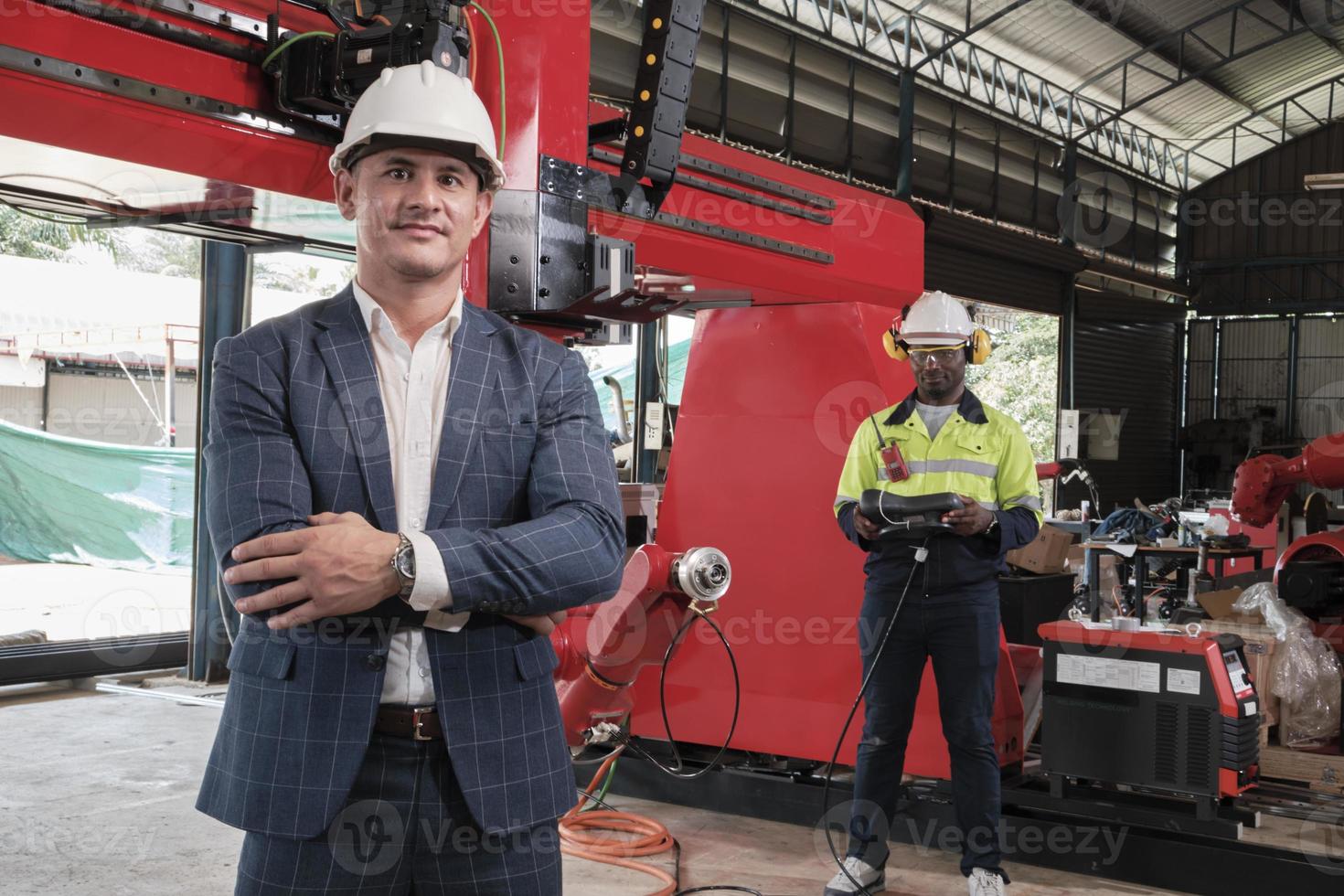 entrepreneur et ingénieur d'affaires masculin blanc fier et réussi avec un bras robotique dans une usine de fabrication mécanique, une machine automatique industrielle intelligente et une innovation technologique futuriste. photo