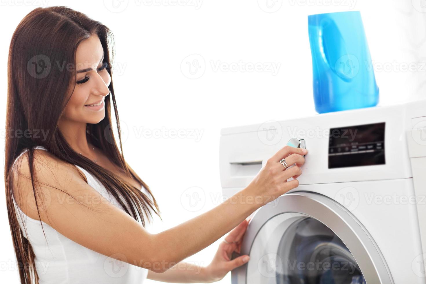 portrait de jeune femme au foyer avec blanchisserie à côté de la machine à laver photo