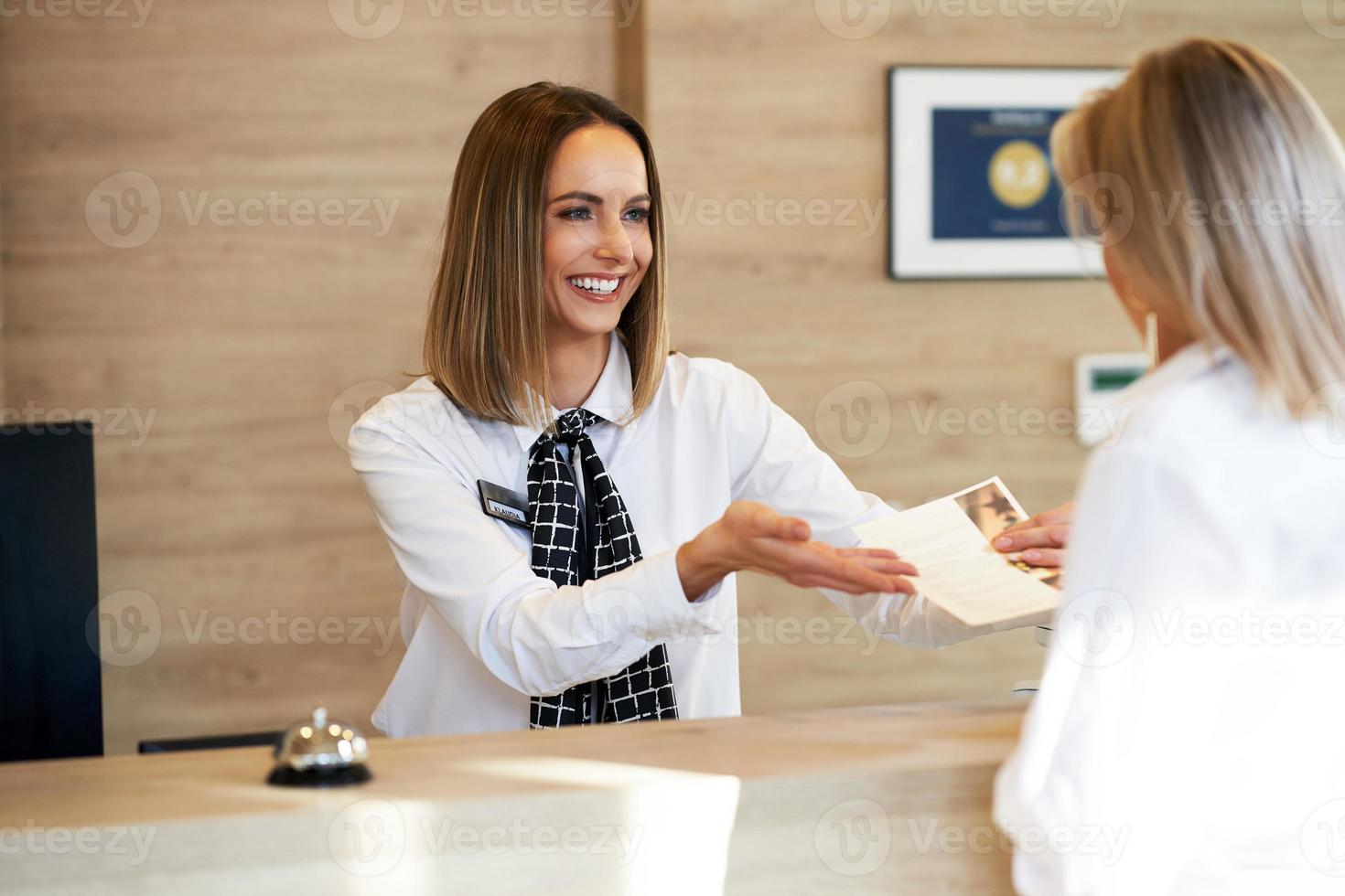 réceptionniste et femme d'affaires à la réception de l'hôtel photo