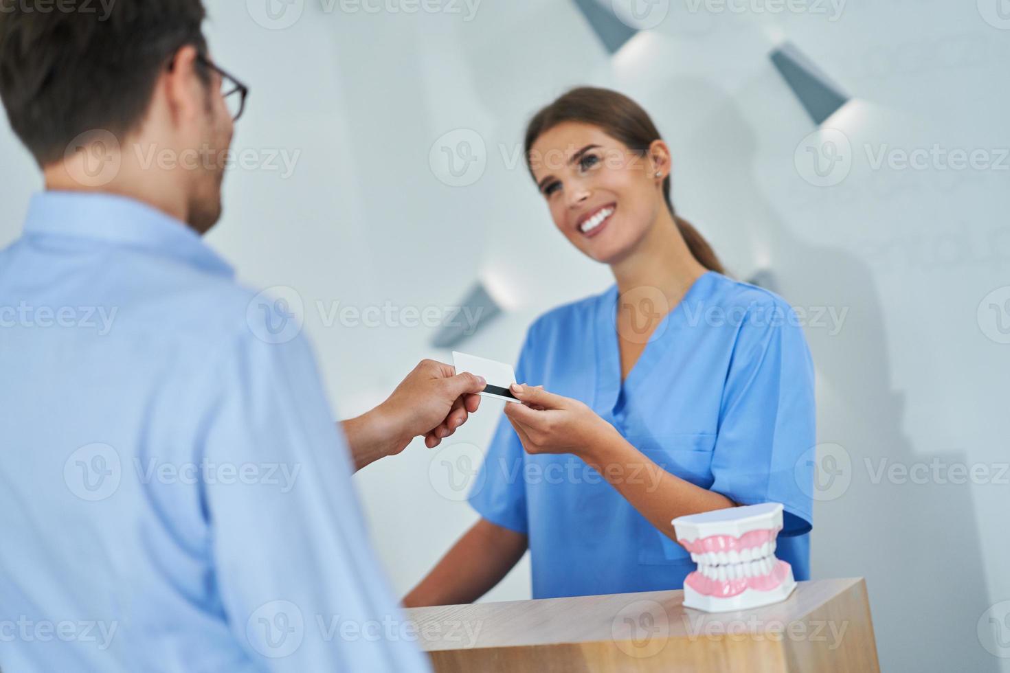 patient payant pour une visite dentaire à la clinique photo