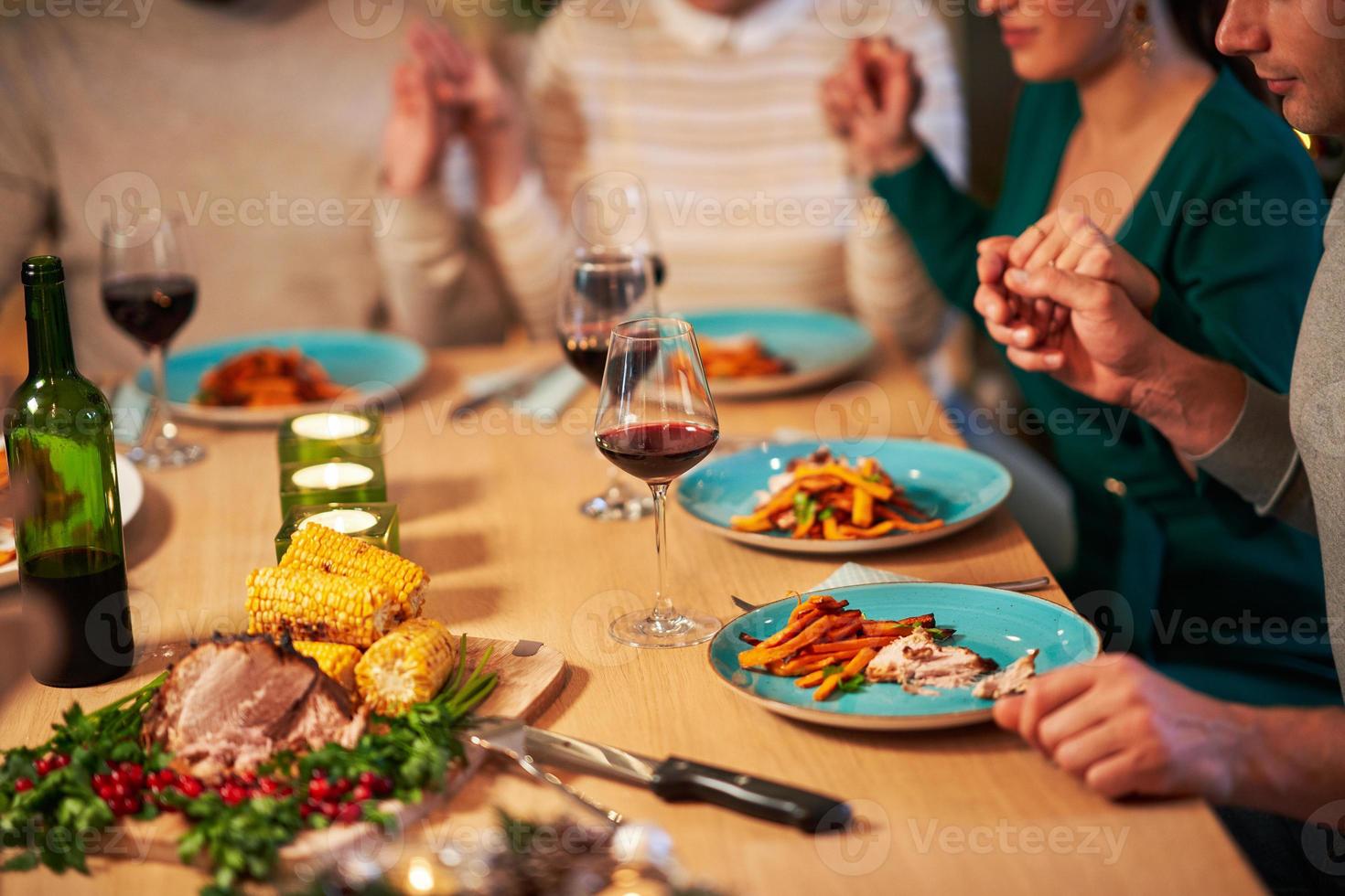 groupe d'amis priant sur la table de thanksgiving de noël à la maison photo