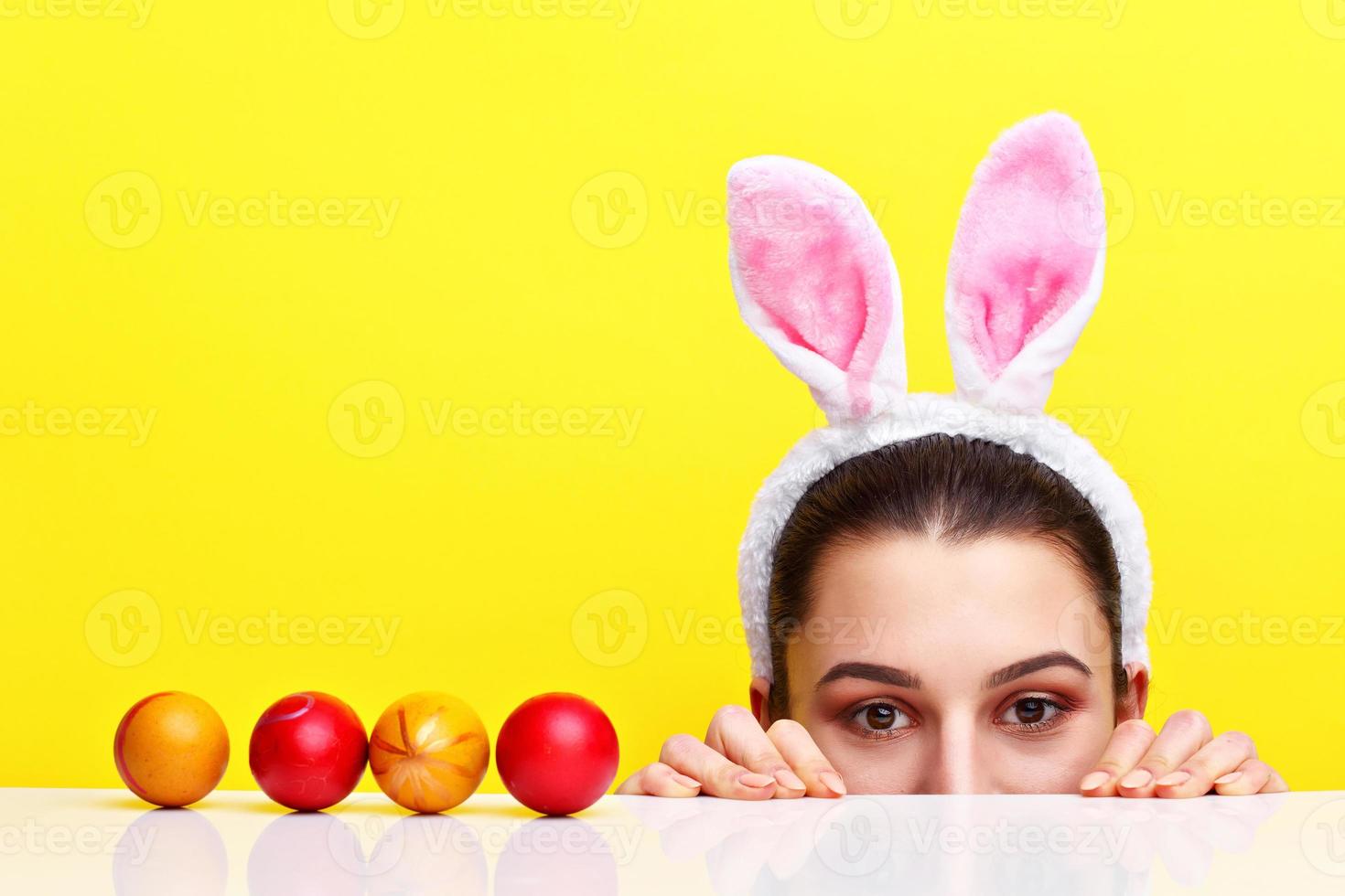 heureuse jeune femme portant des oreilles de lapin et ayant des oeufs de pâques photo