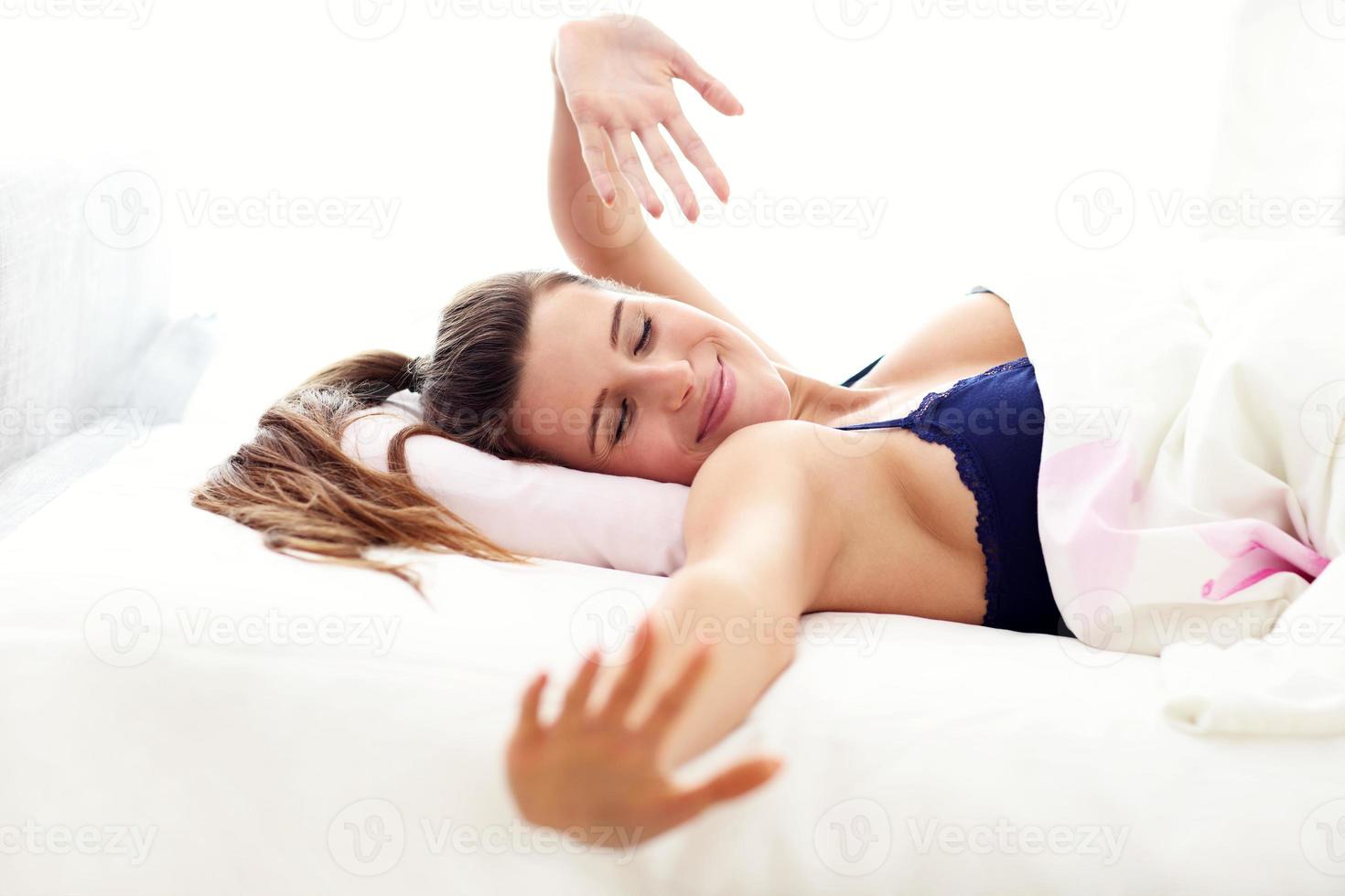 jeune femme se réveillant dans son lit photo