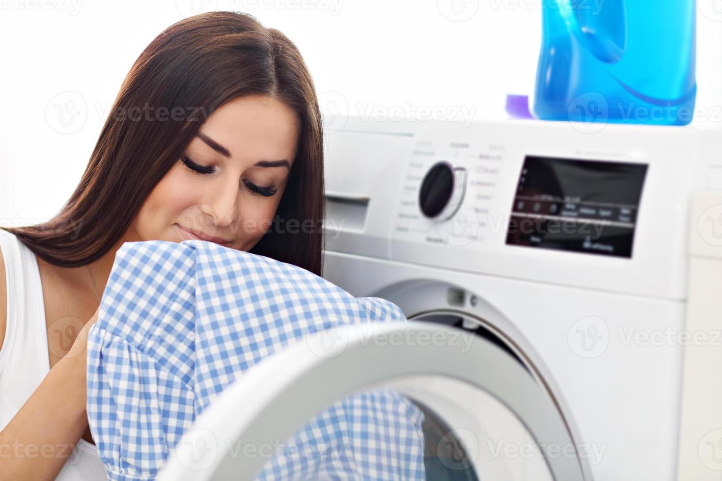 portrait de jeune femme au foyer avec blanchisserie à côté de la machine à laver photo