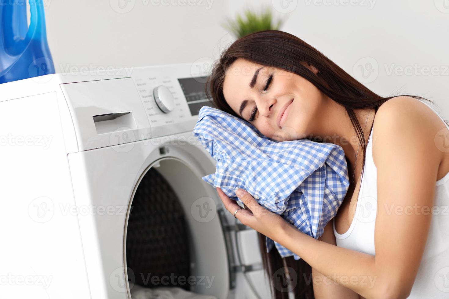 portrait de jeune femme au foyer avec blanchisserie à côté de la machine à laver photo