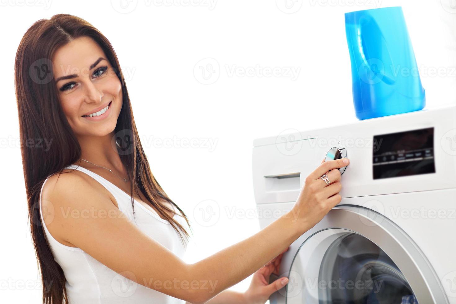 portrait de jeune femme au foyer avec blanchisserie à côté de la machine à laver photo