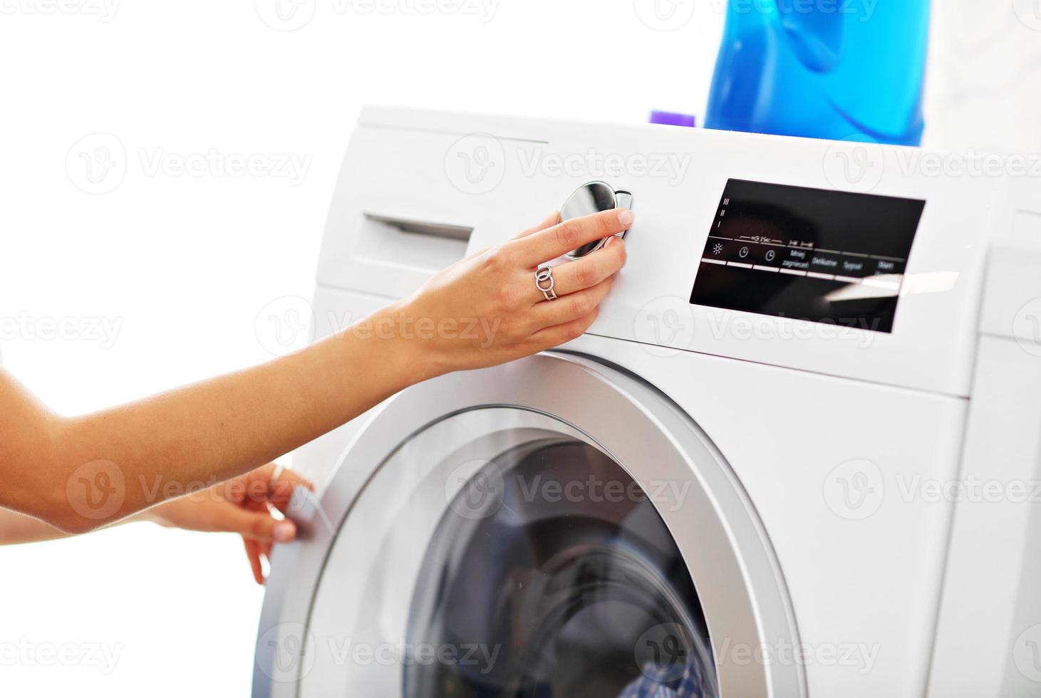 portrait de jeune femme au foyer avec blanchisserie à côté de la machine à laver photo