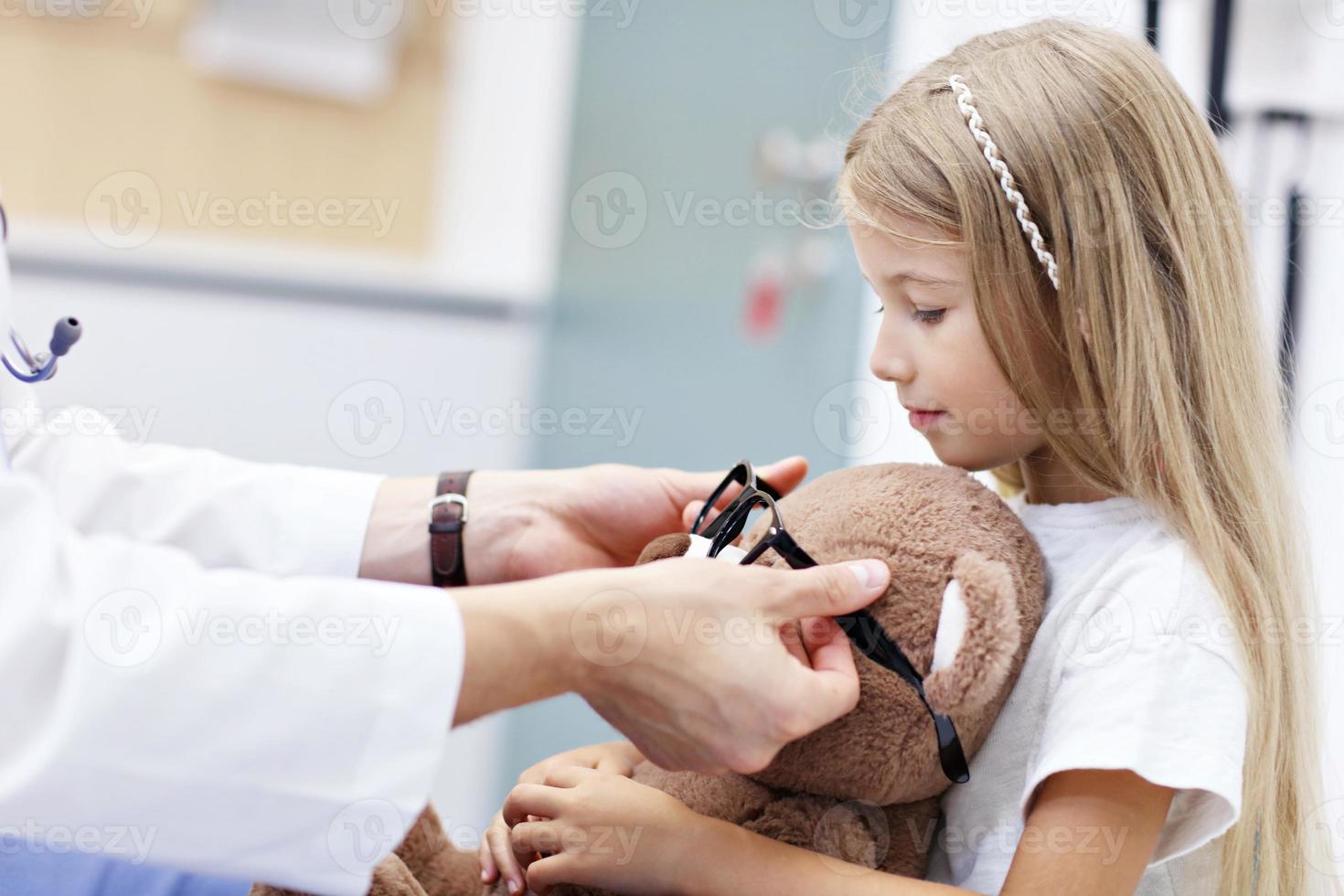 L'optométriste masculin d'enfant examine la vue de la petite fille photo