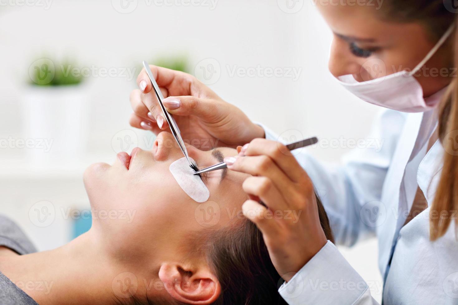 femme adulte ayant une extension de cils dans un salon de beauté professionnel photo