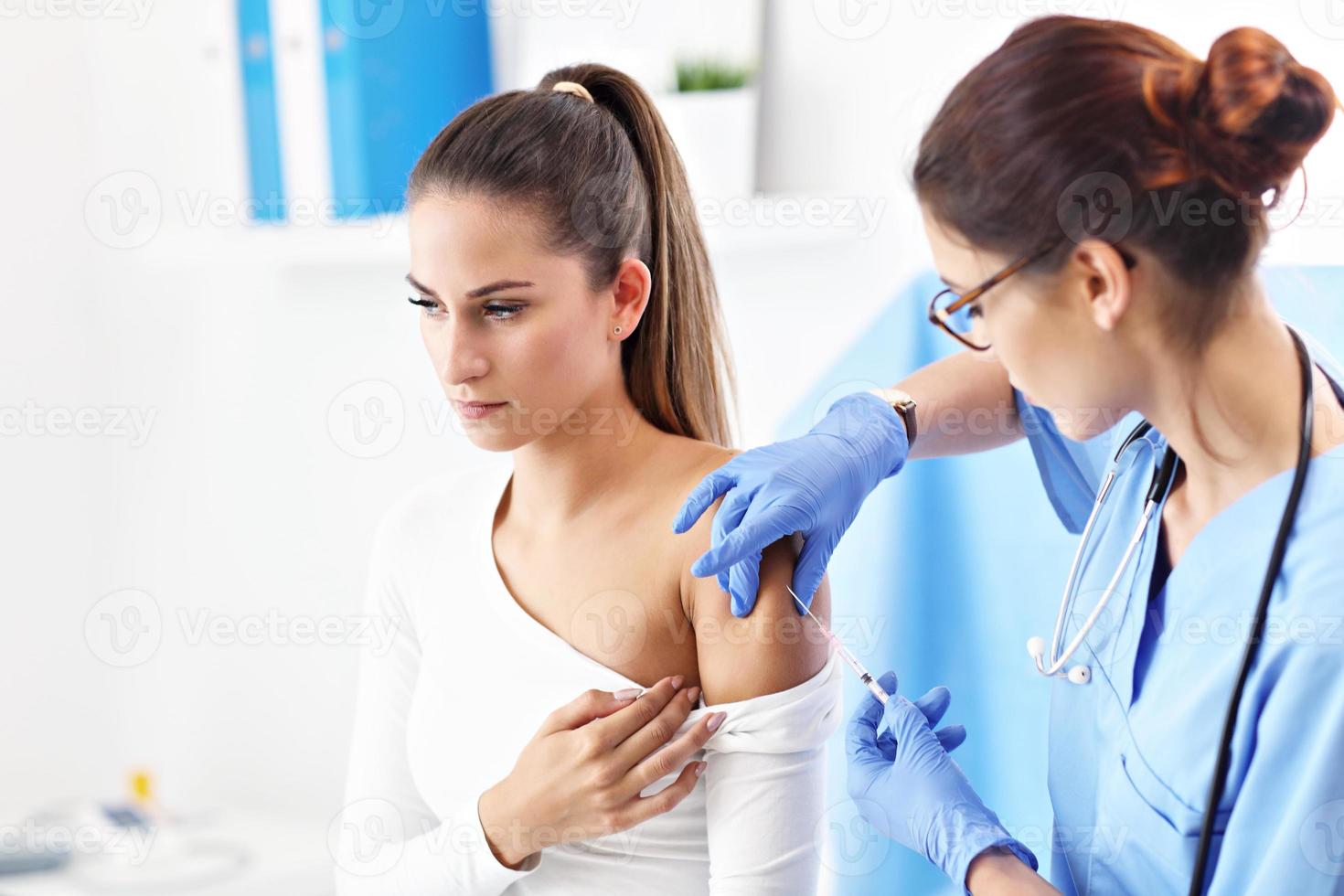 femme adulte ayant une injection lors d'une visite au bureau d'une femme médecin photo