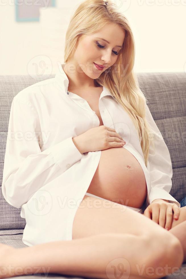 femme enceinte heureuse reposant sur un canapé photo