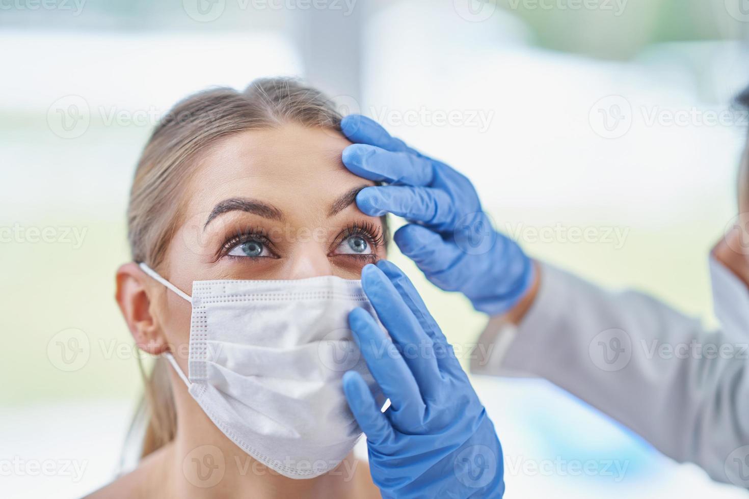 ophtalmologiste en masque vérifiant une patiente photo