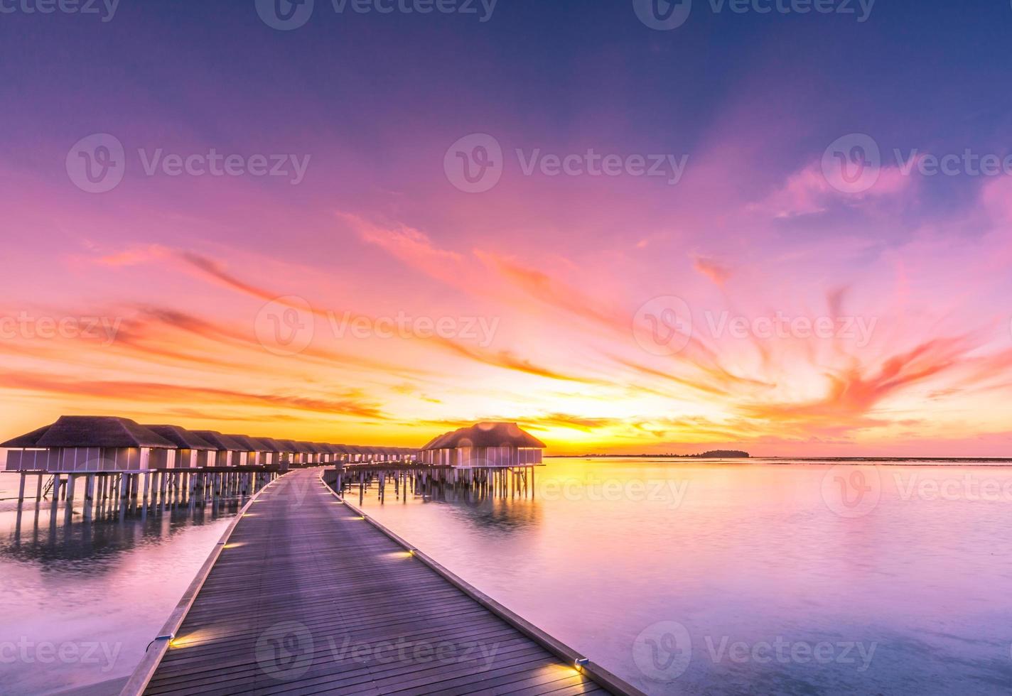 coucher de soleil sur l'île des maldives. complexe de bungalows sur pilotis à la plage des îles. océan indien, maldives. beau paysage de coucher de soleil, complexe de luxe et ciel coloré. coucher de soleil artistique sur la plage sous un ciel magnifique photo