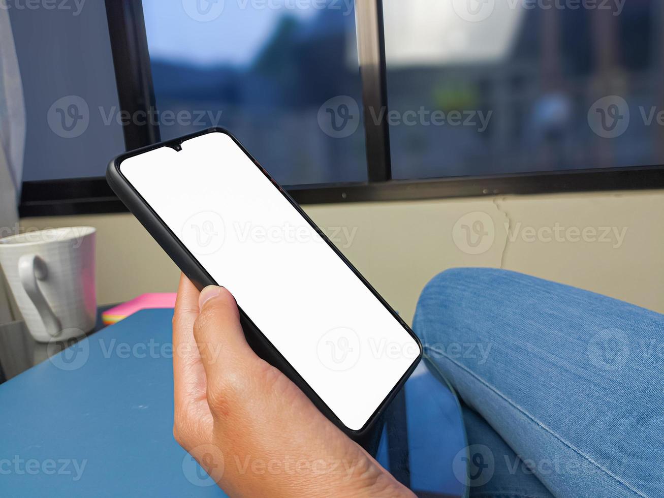 gros plan d'une main de femme tenant un écran blanc de smartphone est vierge .maquette. photo