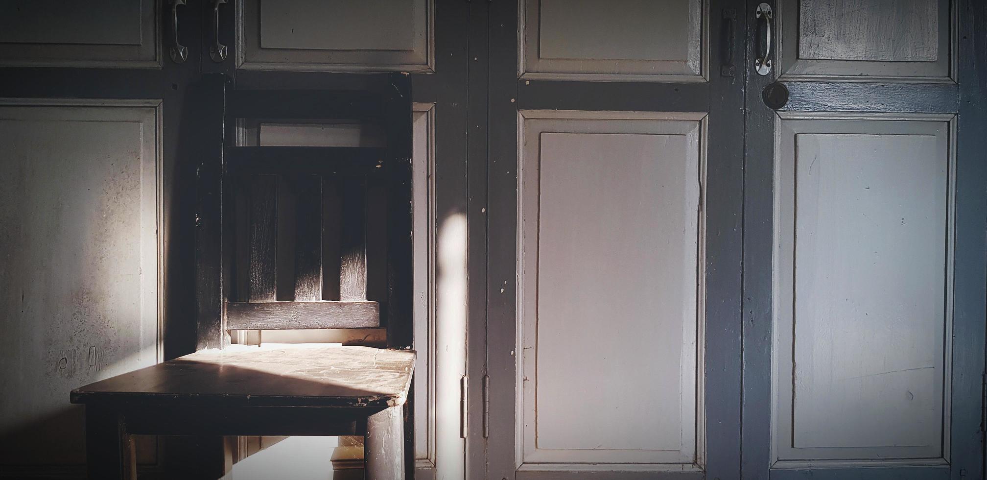 chaise en bois à l'ombre du soleil sur une porte vintage ou classique. objet rétro avec lumière le matin. photo