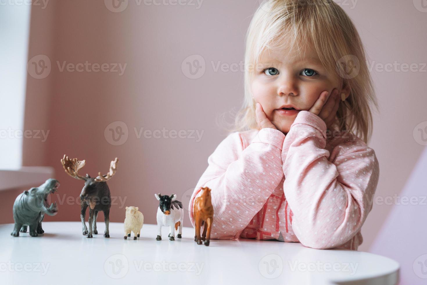 petite fille tout-petit en rose jouant avec des jouets d'animaux sur la  table dans la chambre des enfants à la maison 15930860 Photo de stock chez  Vecteezy