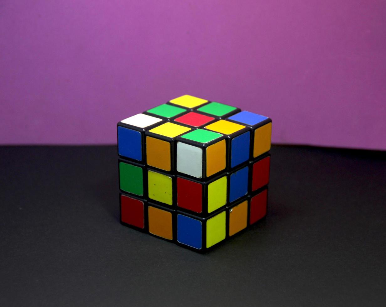 jeu de cube rubik non résolu pour entraîner le cerveau. photo de formation logique éducative amusante isolée sur fond d'écran de surface violet et noir.