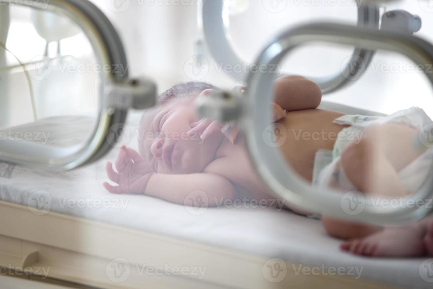 un nouveau-né se trouve dans des boîtes à l'hôpital. un enfant dans une couveuse. unité de soins intensifs néonatals et prématurés photo