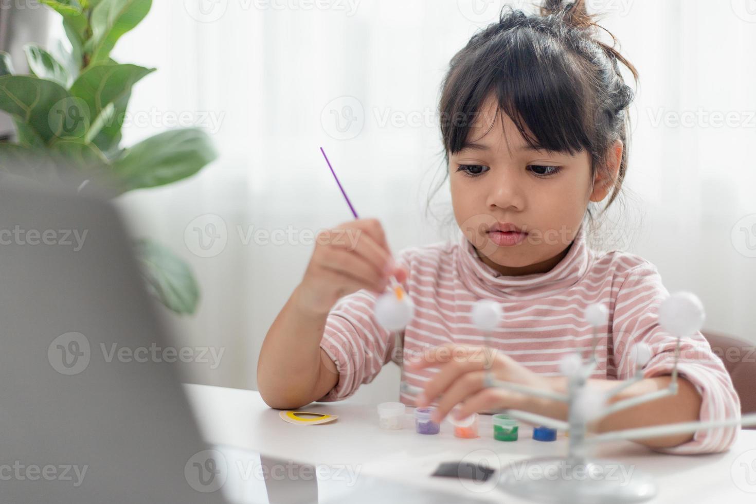 une petite fille asiatique étudie le système solaire en cours de géographie. en regardant le modèle à l'échelle des planètes photo