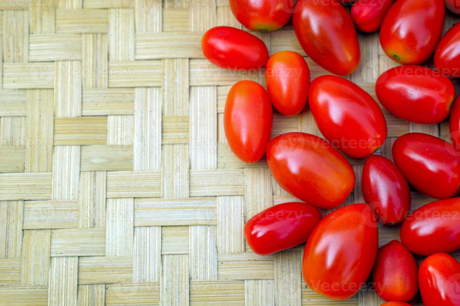 tomates mûres rouges fraîches sur un fond de tissage de bambou. mise au point douce et sélective. photo