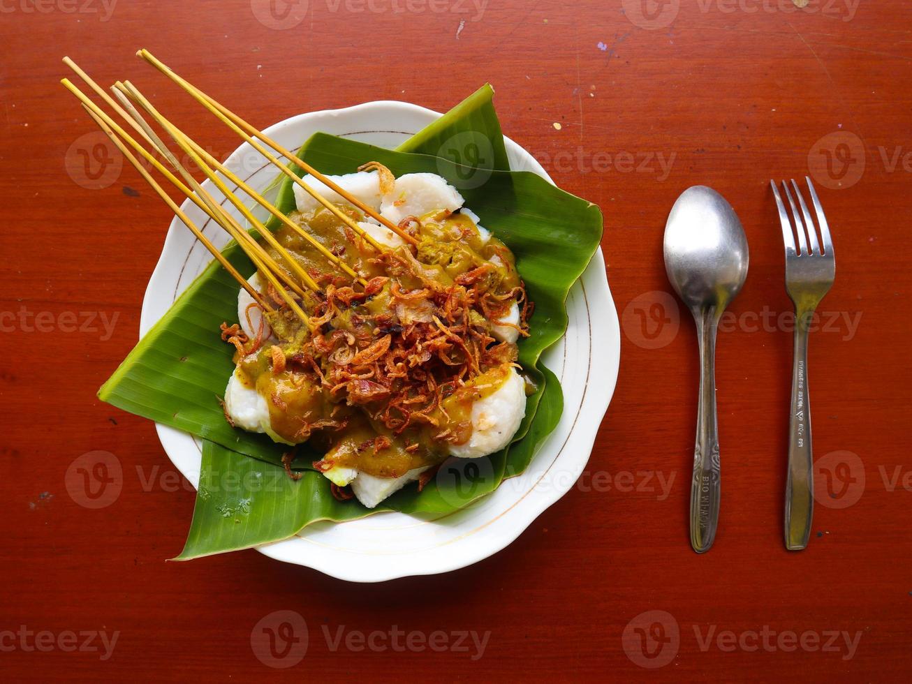 sate padang ou satay padang est un satay de bœuf épicé de padang, à l'ouest de sumatra. servi avec sauce curry épicée et galette de riz, longong sur feuille de bananier. isolé sur fond blanc photo