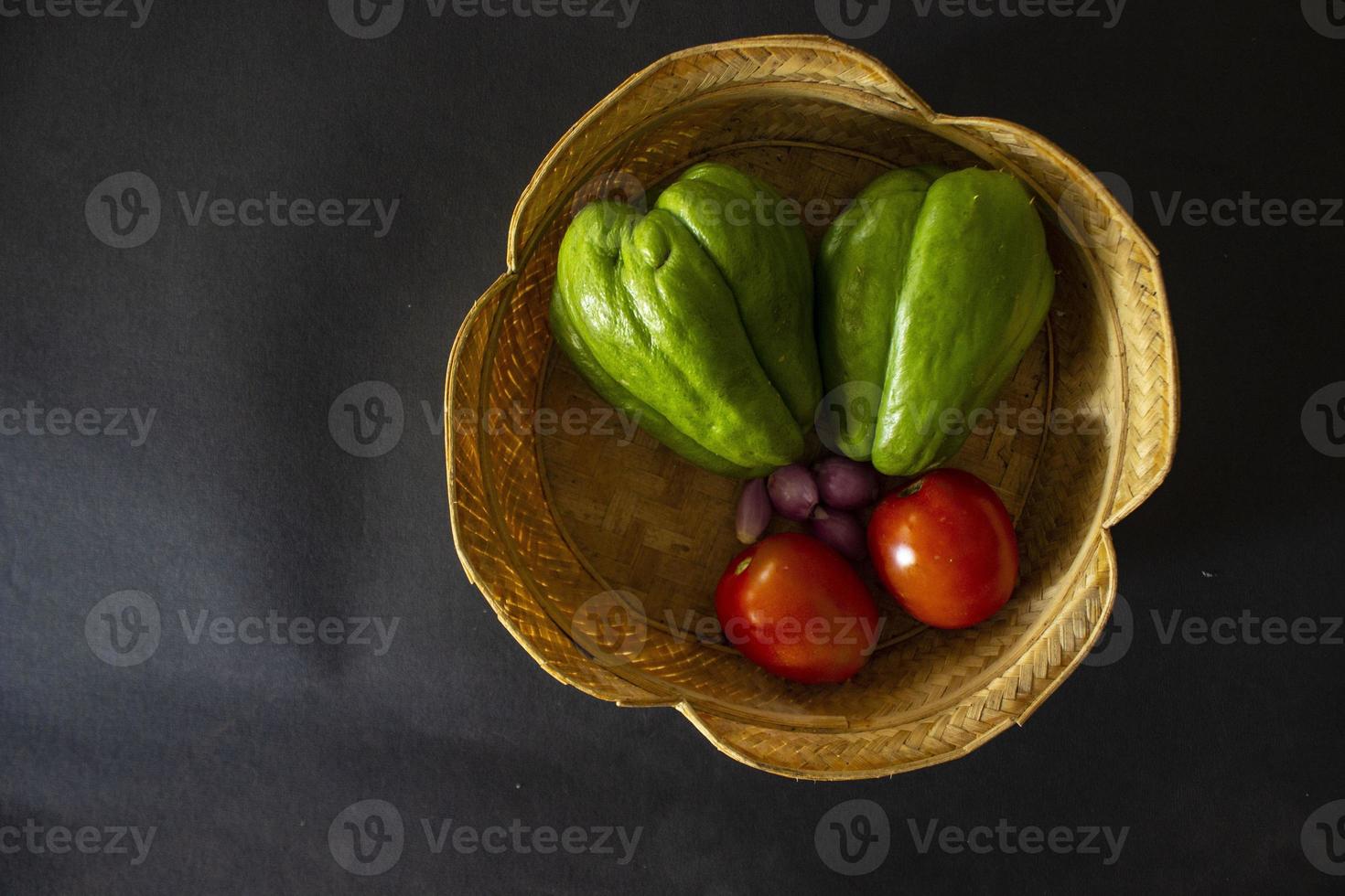 tomates tropicales avec jipang ou labu siam ou chayote et oignon sont servis dans un panier isolé sur fond noir photo