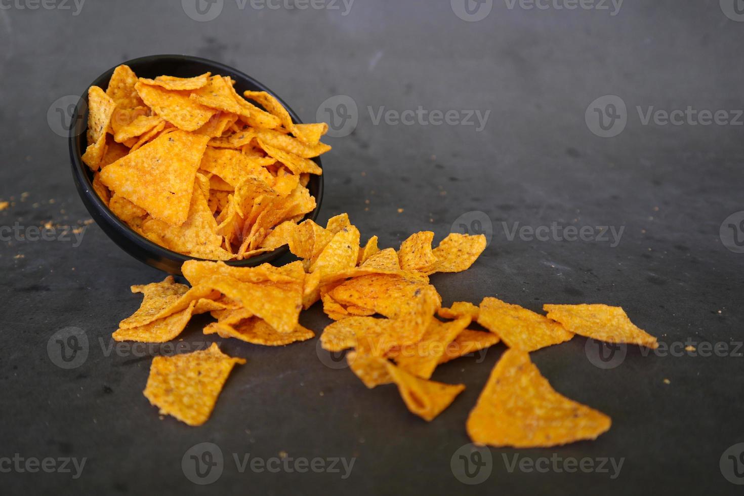 tortilla chips est des croustilles de maïs ou appelez des nachos, servis dans un bol, sur fond noir à base de maïs photo